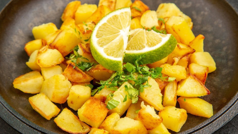 На сковороде лежит посыпанный зеленью жареный картофель с кусочками лайма, который может развалиться, если допустить ошибки при приготовлении